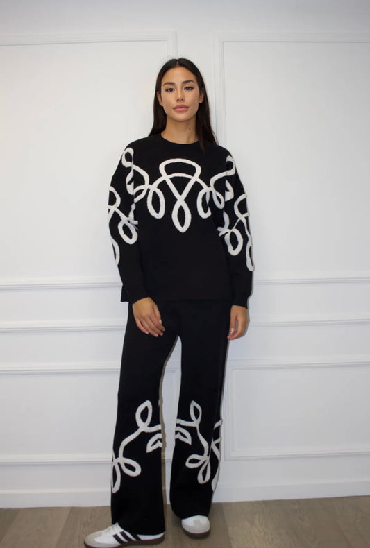 Melns kostīms ar baltiem izšuvumiem 